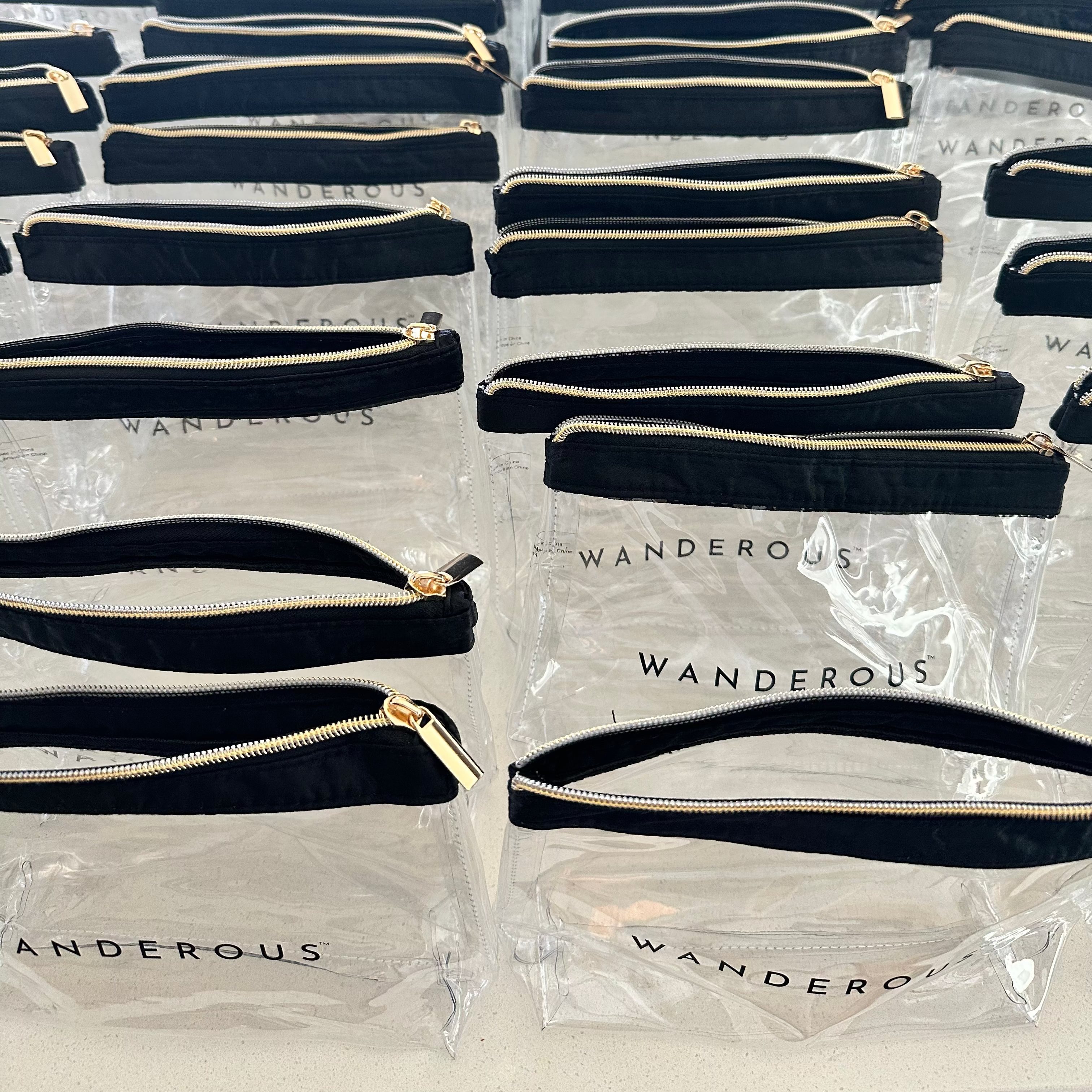 Multiple black wristlets with gold zippers in clear packaging labeled 'Wanderous'.